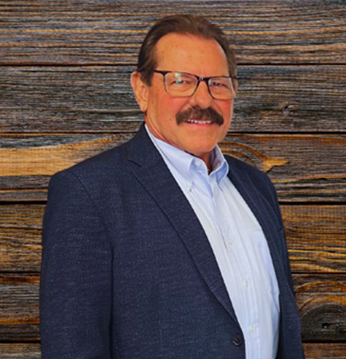 A man wearing glasses and a suit, smiling for the camera.